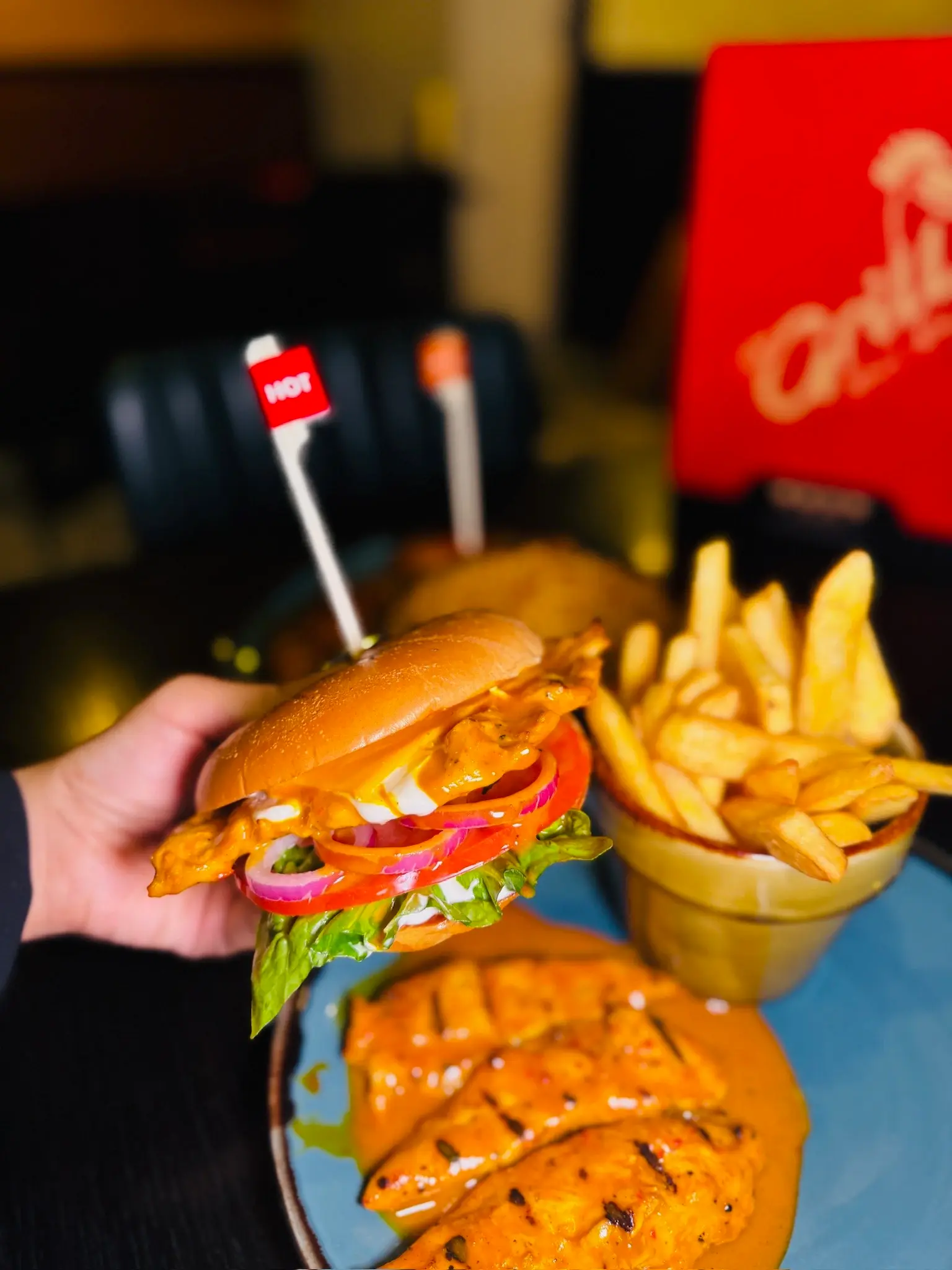 Close-up of a peri peri chicken burger with hot sauce, chips and flame-grilled chicken fillets